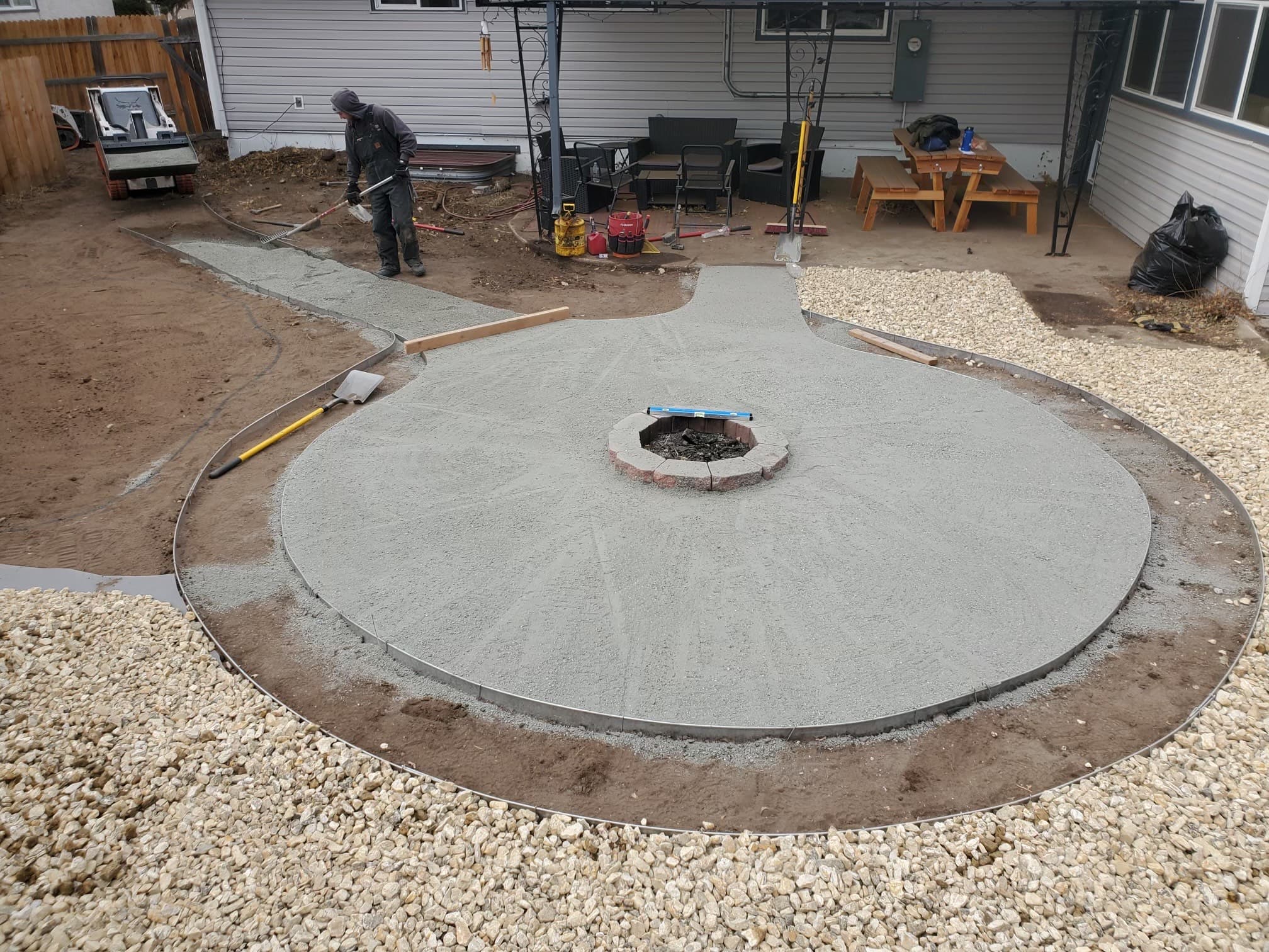 Circular stamped concrete patio with fire pit being installed