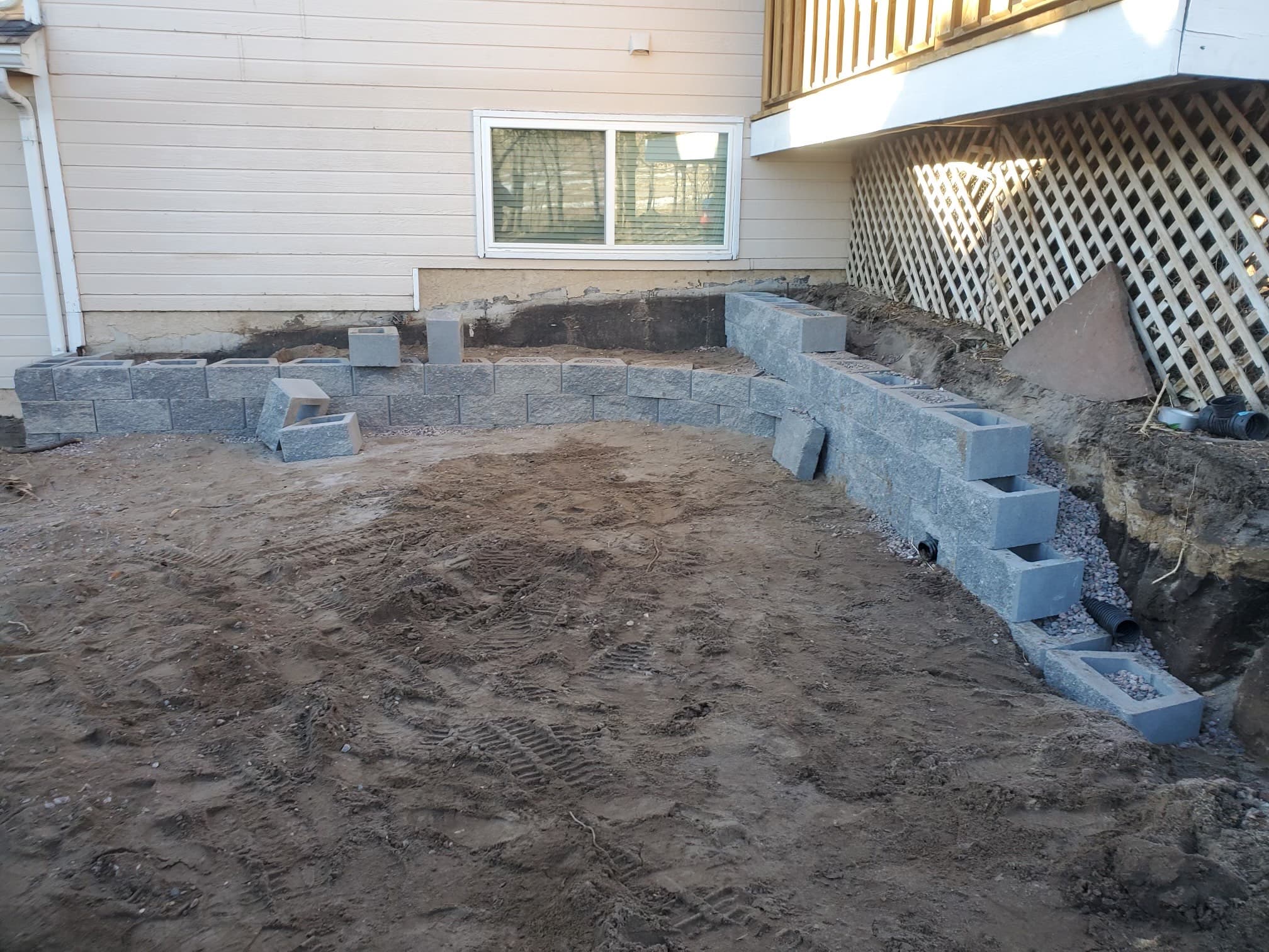 Custom patio with fire pit and retaining wall in backyard